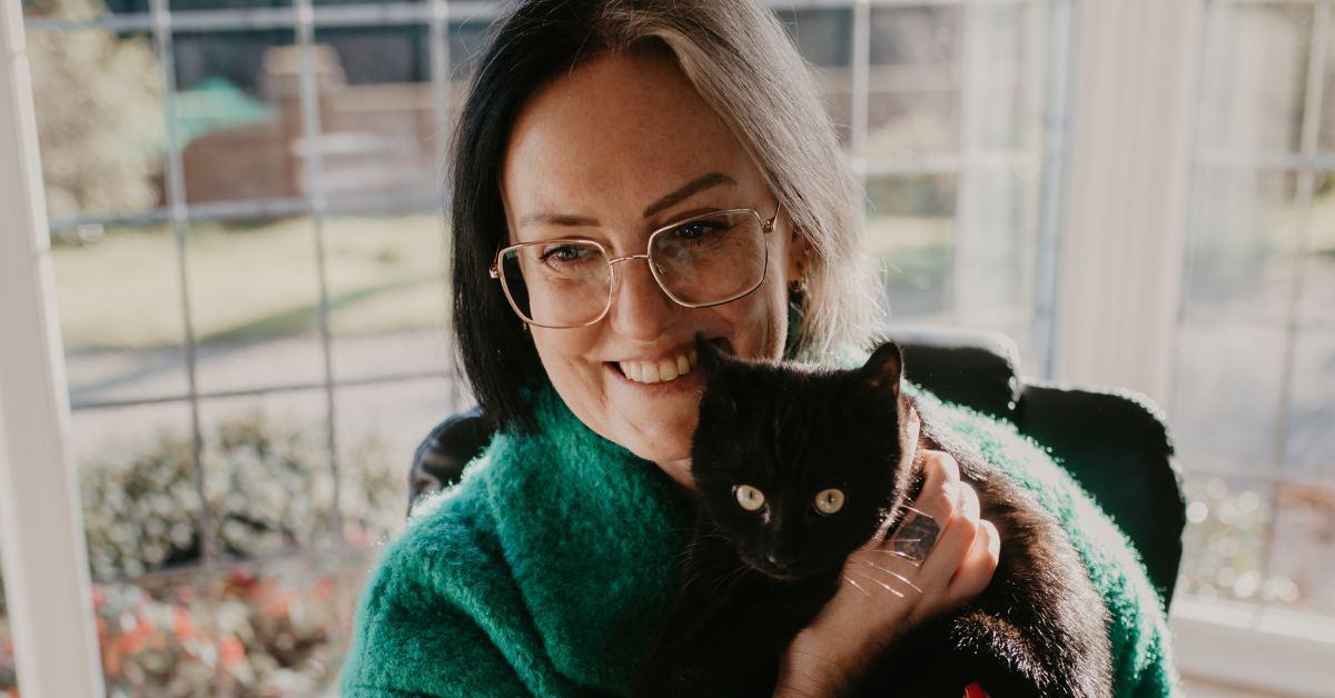 Lady wearing green coat with a black cat.